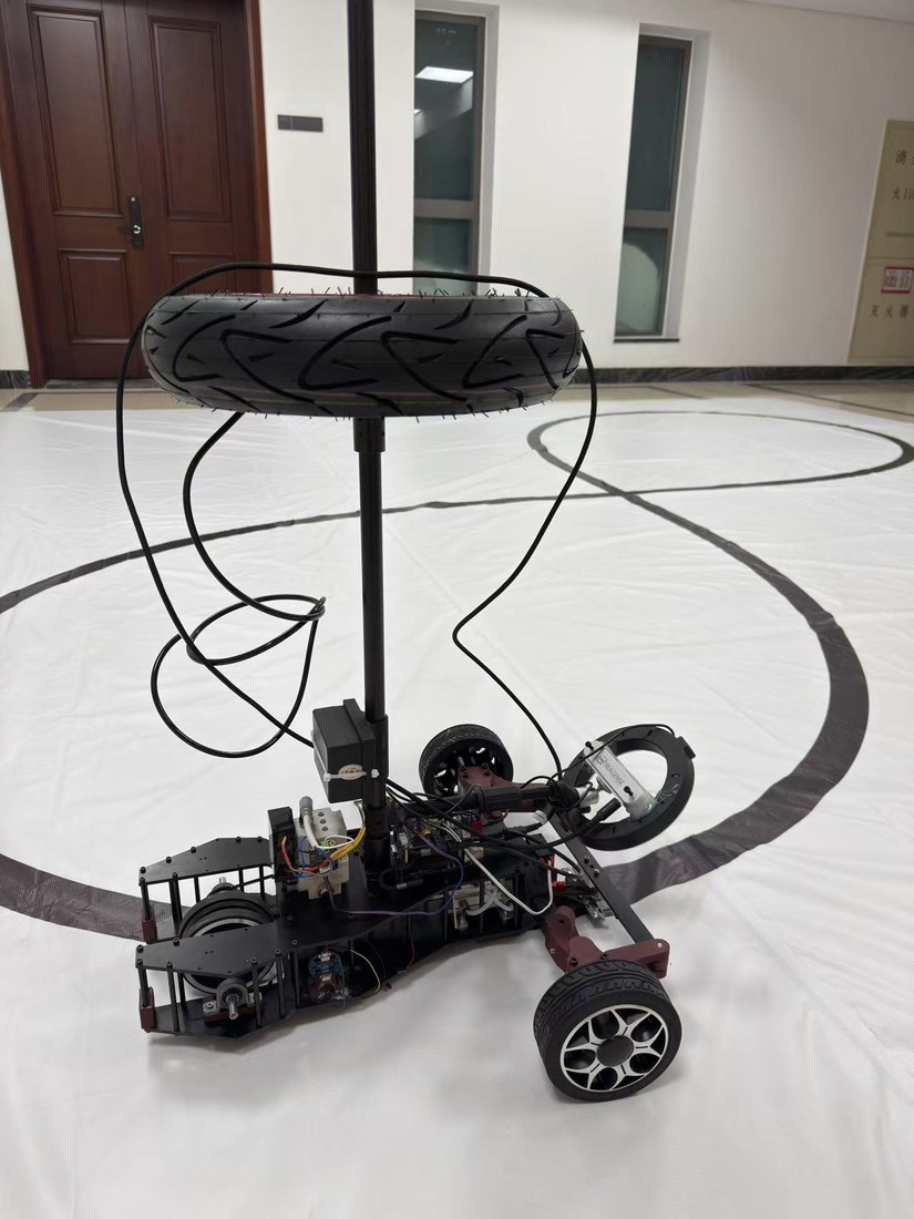 The car on the test track: a low carbon-fiber chassis with a single tall support column, a scooter tire slid over the top of that column serving as the air store, air lines running down it, and a black painted lane curving across the white floor.