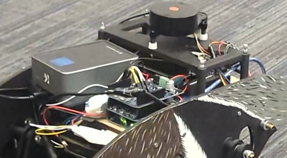 Close view of the robot's electronics deck: the LiDAR on its mast at the back, the Jetson enclosure on the left, and a stack of boards in the middle held down over the chassis plate.