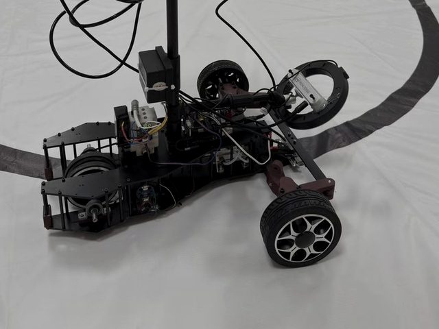 The compressed-air car on the white test track, drivetrain and air lines exposed.
